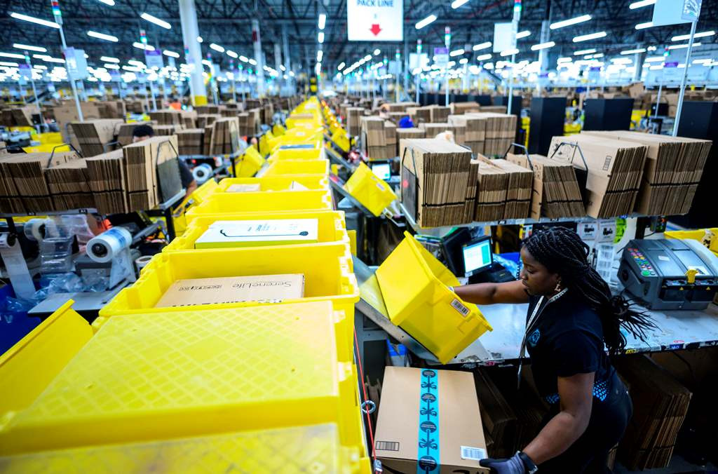 Seorang perempuan tengah mengepak barang di gudang milik Amazon di Staten Island, New York City. Foto: AFP/Johannes Eisele