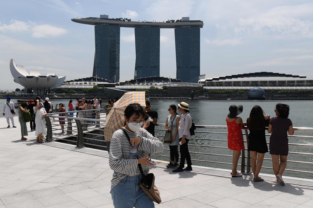 Seorang turis mengenakan masker saat berkunjung ke Merlion Park, Singapura, 17 Februari 2020. (Foto: AFP/ROSLAN RAHMAN)