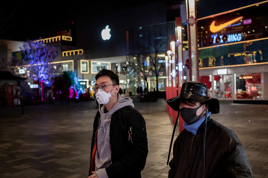 Warga mengenakan masker saat berjalan di salah satu pusat perbelanjaan di Beijing, Tiongkok, 24 Februari 2020. (Foto: AFP/NICOLAS ASFOURI)