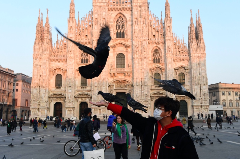 Seorang pria di Milan, Italia menggunakan masker di tengah ancaman virus korona. Foto: AFP