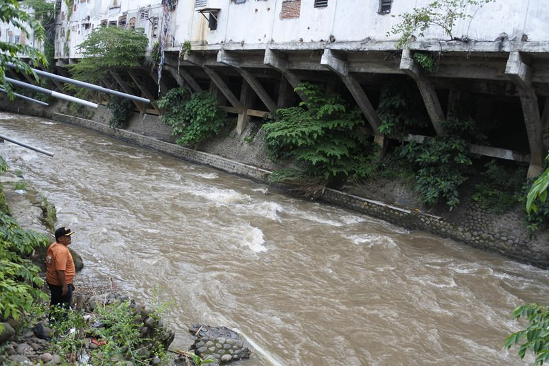 Warga melihat bagian belakang ruko yang berdiri di bantaran Sungai Jompo, Jember, Jawa Timur, sebelum ambruk. (Foto: ANTARA/Seno)