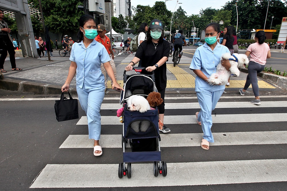 Warga mengenakan masker bersama hewan peliharaannya di area hari bebas kendaraan bermotor di kawasan Thamrin, Jakarta, Minggu, 9 Februari 2020. Foto: MI/Susanto