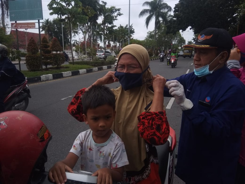 DPW PArtai NasDem Riau membagikan masker ke pengguna jalan di Pekanbaru. Medcom.id-Anwar Sadat Guna
