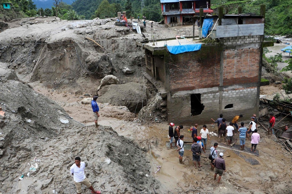 Warga berada di lokasi tanah longsor di desa Jambu, distrik Sindhupalchok, Nepal. (Foto: AFP)