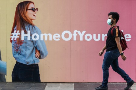 Pejalan kaki menggunakan masker melintasi trotoar di Jalan Jenderal Sudirman, Jakarta, Selasa, 31 Maret 2020. Foto: Antara/Rivan Awal Lingga