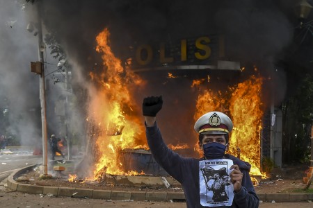 Pengunjuk rasa berfoto dengan latar belakang api yang membakar pos polisi saat demonstrasi menentang UU Cipta Kerja di kawasan Patung Kuda, Jakarta, Kamis, 8 Oktober 2020. Foto: Antara/Galih Pradipta