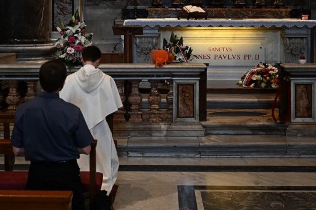 Orang-orang berdoa di makam Paus Yohanes Paulus II di Basilika Santo Petrus, Vatikan, pada 18 Mei 2020. (Vincenzo PINTO/AFP)