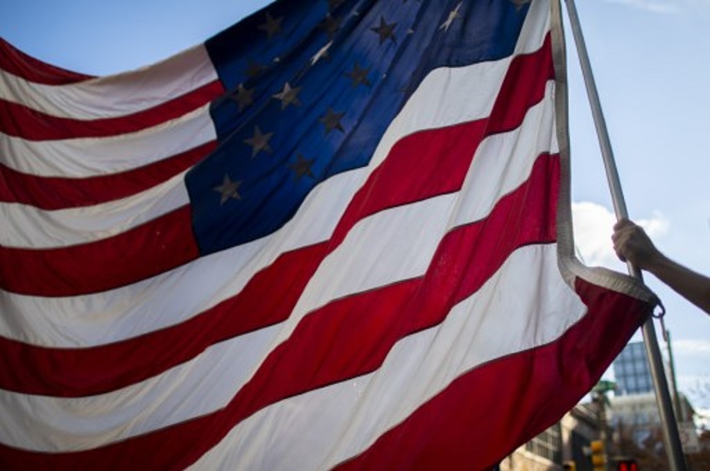 Pendukung Donald Trump mengikatkan bendera Amerika Serikat dalam sebuah aksi unjuk rasa di Philadelphia, Pennsylvania pada Selasa, 10 November 2020. (Mark Makela/Getty/AFP)