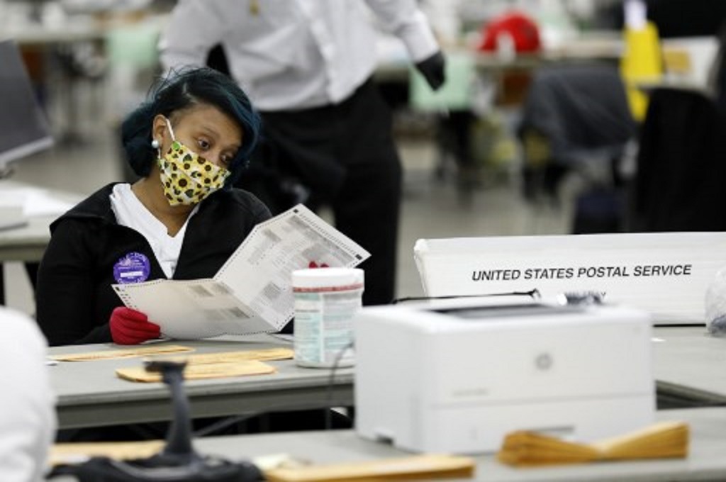 Seorang petugas sedang menghitung surat suara di salah satu pusat penghitungan di Detroit, Michigan pada 4 November 2020. (JEFF KOWALSKY/AFP)