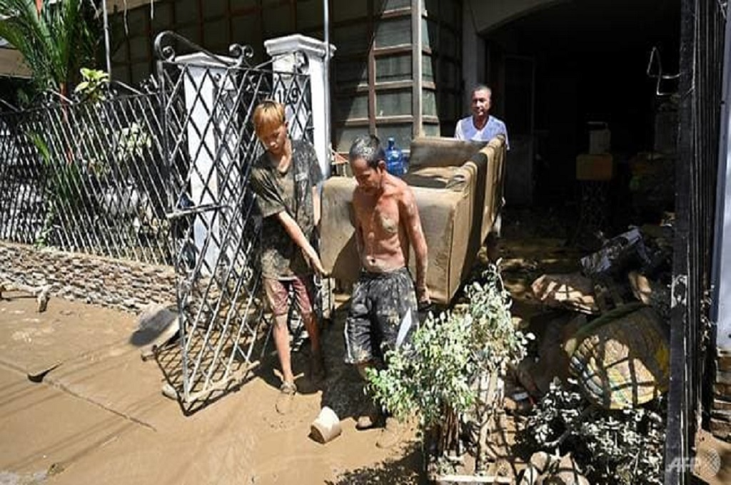 Warga membersihkan salah satu rumah yang terkena banjir akibat terjangan Topan Vamco di Filipina. (AFP/Ted Aljibe)