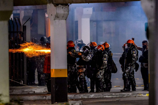 Petugas menembakkan gas air mata untuk membubarkan massa yang mulai beringas di pintu masuk supermaket Carrefour, tempat Joao Alberto Silveira Freitas dipukuli hingga tewas di Porto Alegre, Rio Grande do Sul, Brasil, pada  Jumat, 20 November 2020 waktu se