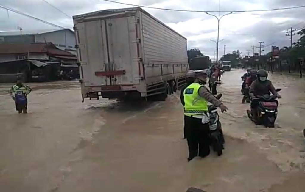 Petugas Satlantas Polres Tegal saat mengatur lalu lintas di tengah bencana banjir di Jalan Pantura, Desa Kedungkelor, Kecamatan Warureja, Kabupaten Tegal, Jawa Tengah. (Medcom.id/Kuntoro Tayubi)