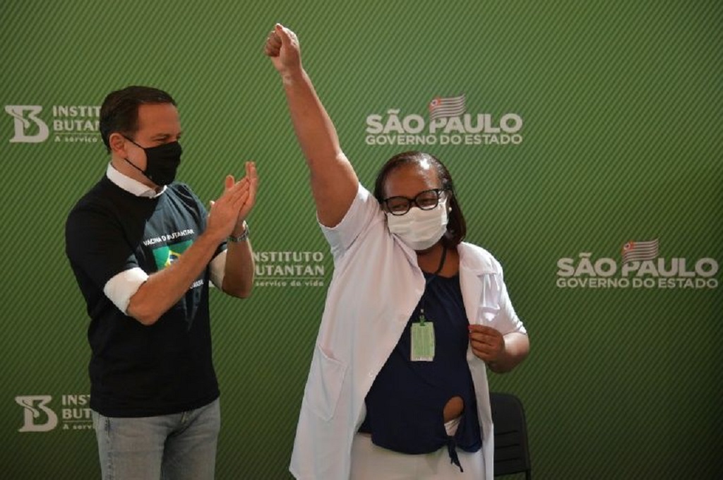 Monica Calazans (tengah) berpose usai disuntik vaksin covid-19 di Brasil pada 17 Januari 2021. (AFP)