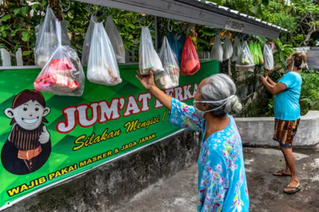 Beberapa orang mengambil paket bahan makanan gratis yang digantung di pagar rumah warga di Kelurahan Lempongsari, Gajahmungkur, Semarang, Jawa Tengah, 23 Oktober 2020. ANTARA FOTO/Aji Styawan/pras.