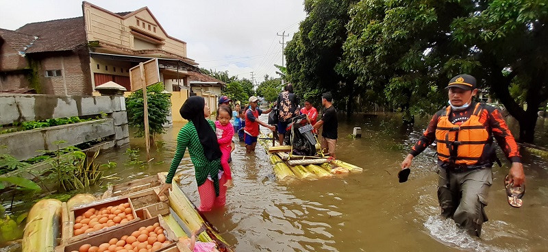 Warga menggunakan rakit batang pohon pisang untuk memindahkan harta benda dan berbelanja kebutuhan harian di tengah banjir. (Foto: Medcom.id/Rhobi)