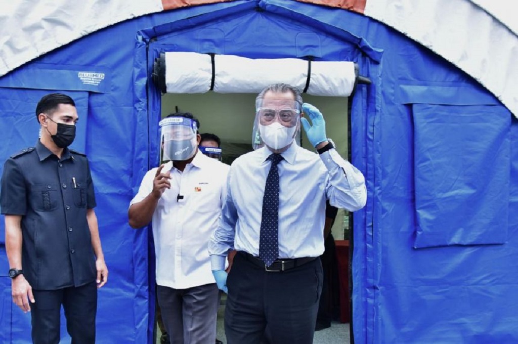 PM Malaysia Muhyiddin Yassin (tengah) usai keluar dari sebuah tenda tempat dilakukannya tes Covid-19. (MALAYSIA DEPARTMENT OF INFORMATION/AFP)