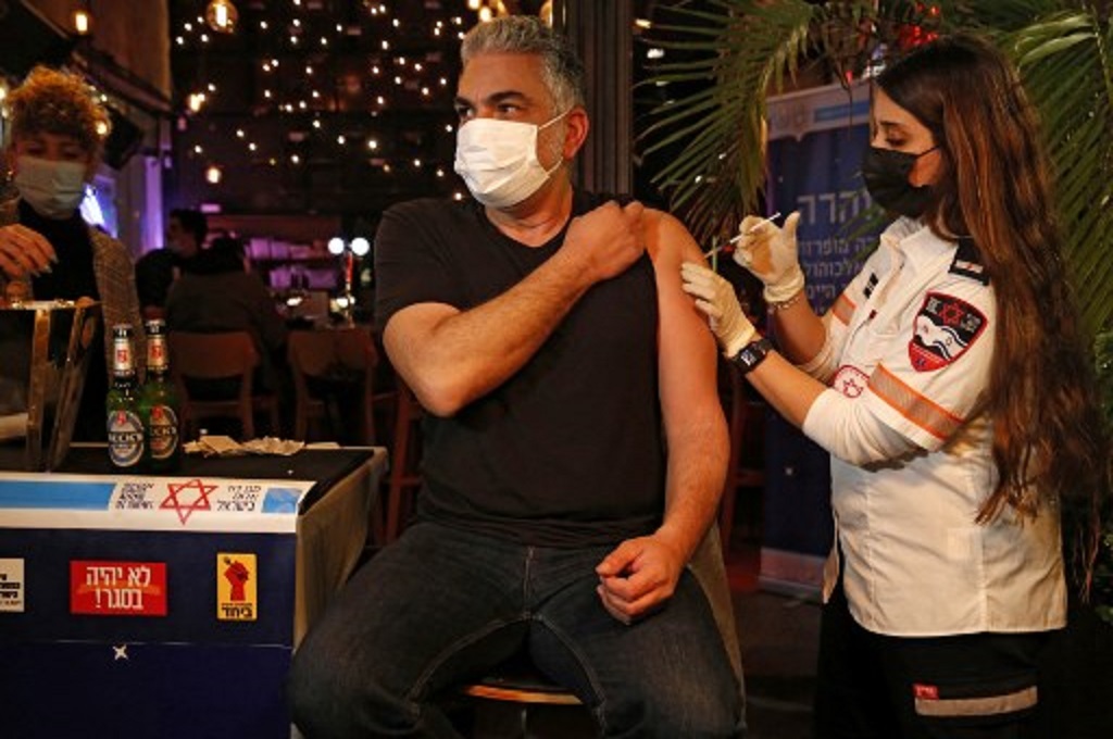 Seorang tenaga kesehatan menyuntikkan vaksin Covid-19 ke pengunjung sebuah bar di Tel Aviv, Israel  pada 18 Februari 2021. (GIL COHEN-MAGEN/AFP)