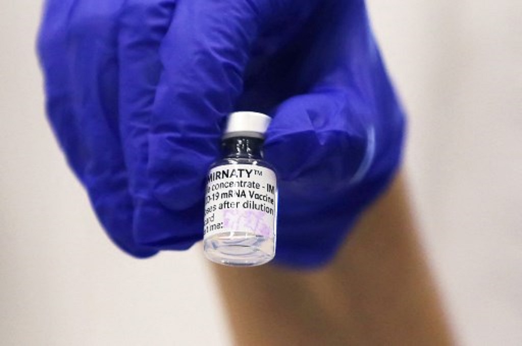 Seorang tenaga kesehatan memperlihatkan satu dosis vaksin Pfizer-BioNTech. (STEVEN SAPHORE/AFP)
