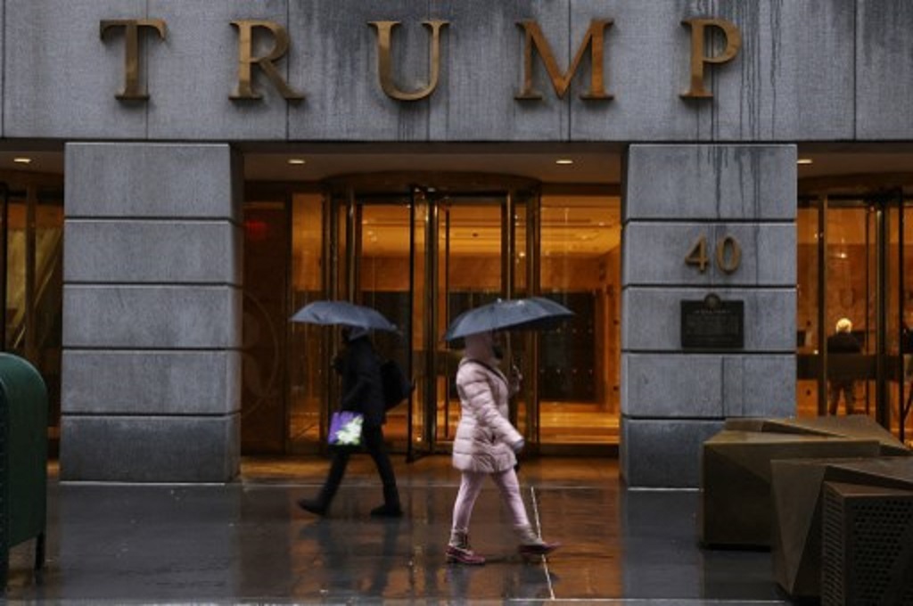 Warga berjalan melewati salah satu properti milik Donald Trump di New York City, AS pada Senin, 22 Februari 2021. (SPENCER PLATT/Getty/AFP)