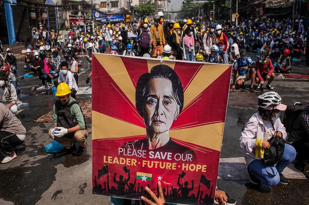 Demonstran membawa poster wajah Aung San Suu Kyi dalam unjuk rasa di kota Yangon, Myanmar pada Selasa, 2 Maret 2021. (AFP)