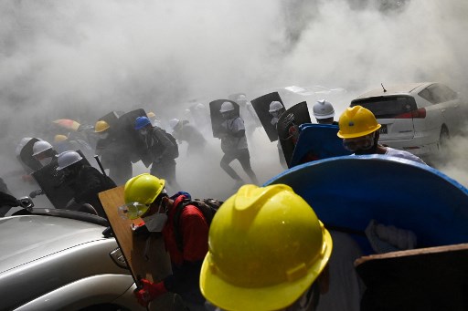 Para pedemo berlindung dari terjangan gas air mata yang ditembakkan pihak keamanan Myanmar. Foto: AFP