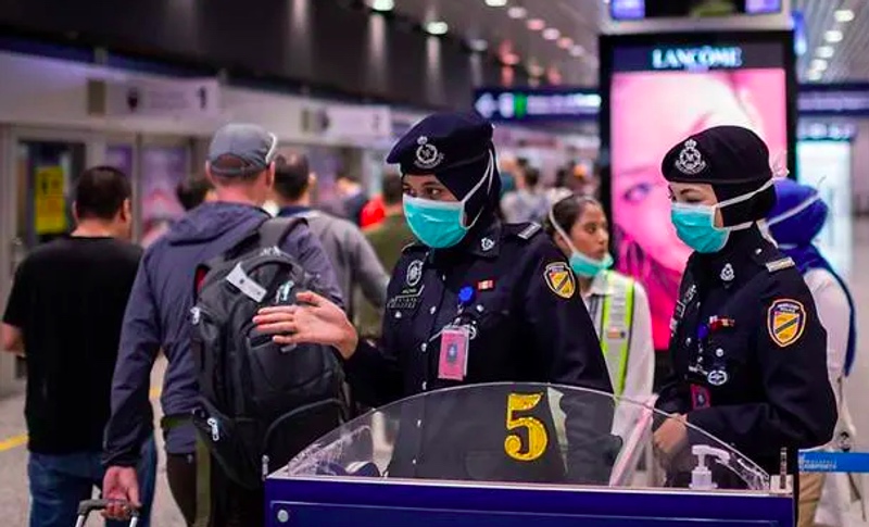 Petugas imigrasi Malaysia memeriksa penggunaan masker oleh warga di KLIA. Foto: AFP