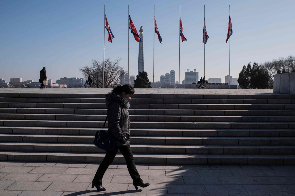Seorang perempuan berjalan melewati deretan bendera di Pyongyang, Korut. (AFP)