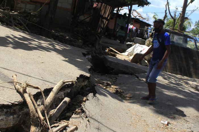 Seorang warga melintasi ruas jalan yang terbelah akibat longsor di Kupang, NTT, Rabu (14/4/2021). (Foto: ANTARA/Kornelis Kaha)