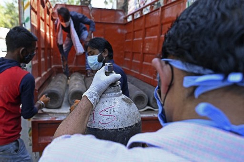 Pekerja mengangkut tabung oksigen medis yang hendak dikirim ke sebuah rumah sakit di New Delhi, India pada 24 April 2021. (Sajjad HUSSAIN / AFP)