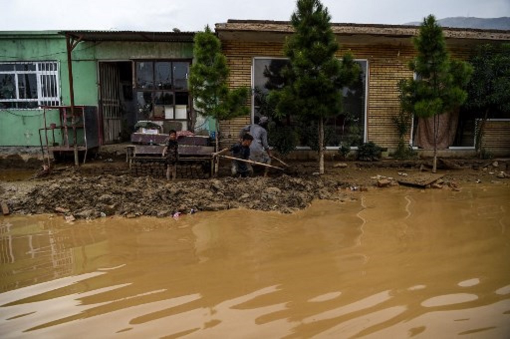 Warga menggunakan sekop untuk membersihkan material lumpur di tengah musibah banjir di Charikar, Afghanistan pada 27 Agustus 2020. (WAKIL KOHSAR / AFP)