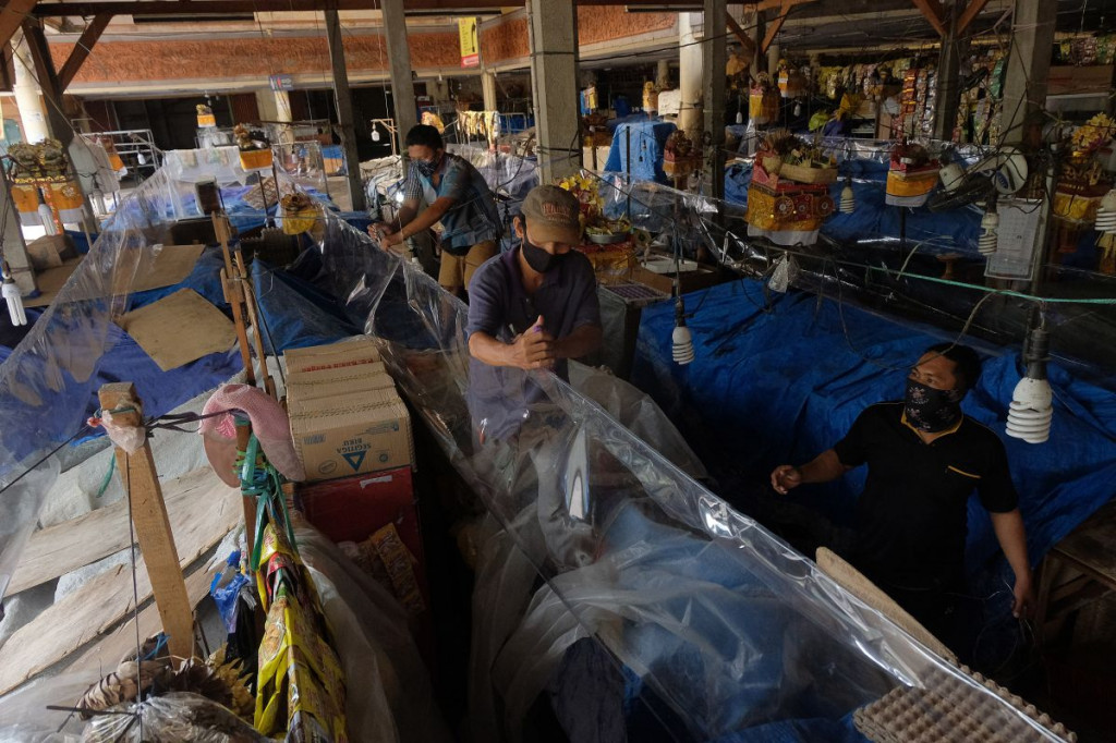Petugas memasang plastik mika untuk menyekat lapak pedagang di pasar tradisional Cokroaminoto Denpasar, Bali, Senin, 15 Mei 2021. Antara/Nyoman Hendra Wibowo