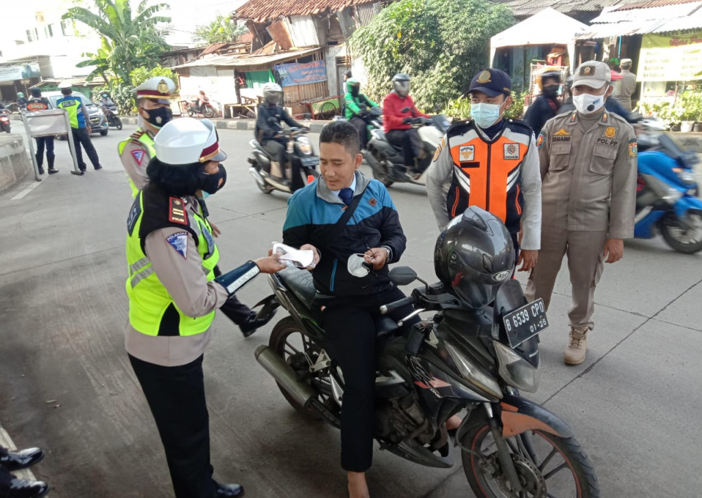 Polisi memberikan masker gratis kepada pengemudi yang tidak menggunakan masker. Foto: TMC Polda Metro Jaya