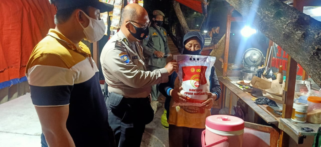 Petugas kepolisian memberikan bantuan beras kepada masyarakat terdampak PPKM darurat di wilayah Cempaka Putih, Jakarta Pusat, Jumat 15 Juli 2021. Medcom.id/Christian