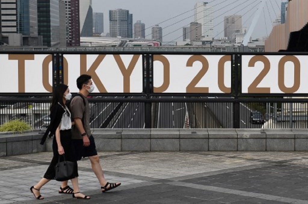 Warga Jepang berjalan melewati logo Olimpiade Tokyo  2020 di Odaiba, 7 Juli 2021. (Kazuhiro NOGI / AFP)