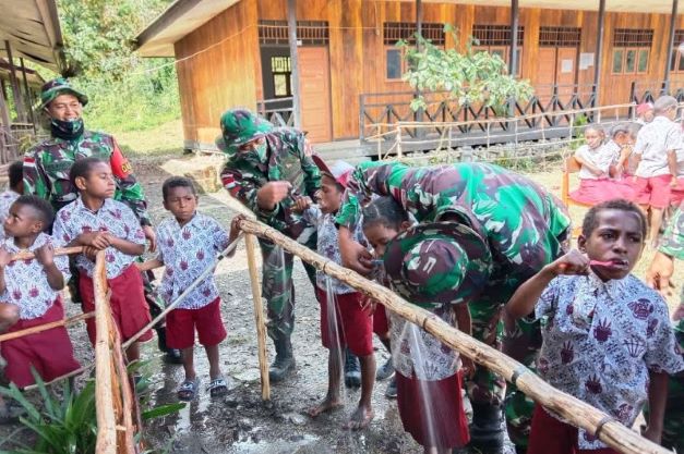 Personel TNI sedang mengajarkan siswa SD YPPK Santa Maria praktik menyikat gigi. Foto: ANT/-Pendam XVII/Cenderawasih