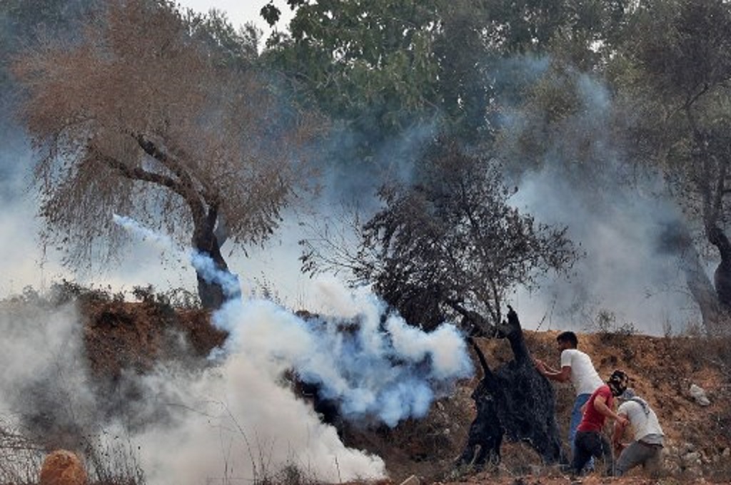Pemuda Palestina melempar balik tabung gas air mata ke arah pasukan Israel dalam bentrokan di Beita, Tepi Barat, 27 Agustus 2021. (JAAFAR ASHTIYEH / AFP)