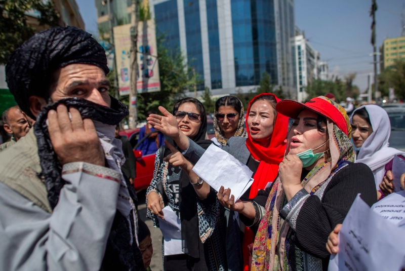Perempuan Afghanistan berhadapan dengan seorang pria saat memprotes pelarangan kerja oleh Taliban. Foto: AFP
