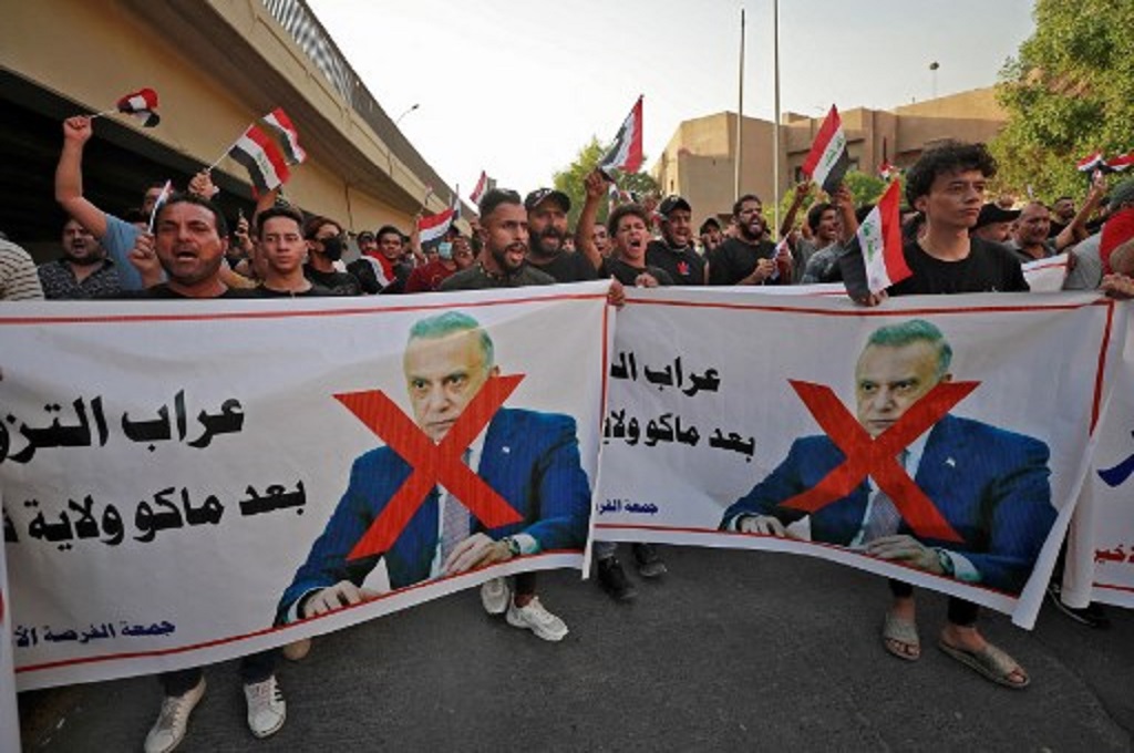 Demonstran anti-pemerintah membawa spanduk bergambar wajah PM Irak Mustafa al-Kadhimi di Baghdad, 5 November 2021. (Ahmad AL-RUBAYE / AFP)