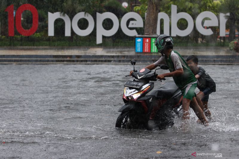  Arsip Foto warga mendorong sepeda motornya yang mogok saat melewati jalanan yang tergenang akibat banjir di Jalan Tambaksari, Surabaya, Jawa Timur, Sabtu, 13 Maret 2021. ANTARA FOTO/Didik Suhartono