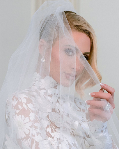 Paris terlihat sangat memukau dalam balutan gaun pengantin yang panjang menjuntai dengan hiasan kelopak bunga yang indah. (Foto: Dok. Instagram/@parishilton)