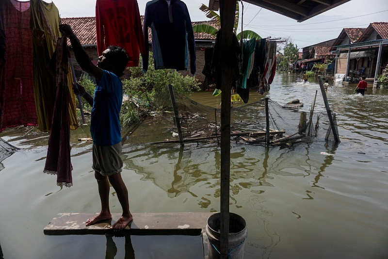 Warga menjemur pakaian di teras rumahnya yang tergenang banjir di Degayu, Pekalongan, Jawa Tengah. (Foto: ANTARA/Harviyan Perdana)