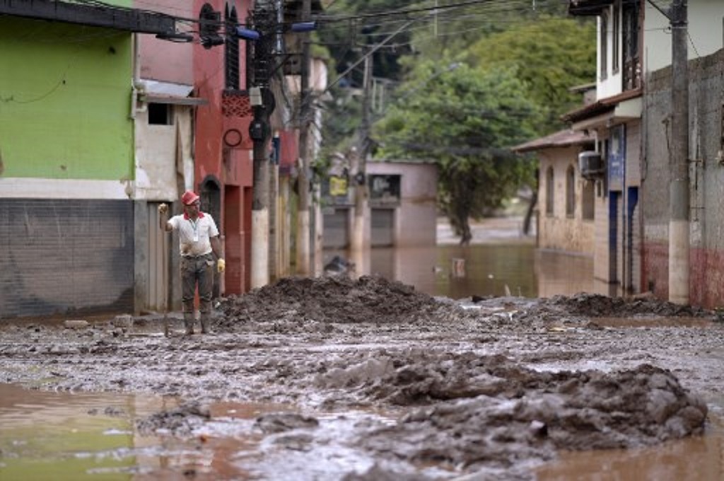 Seorang pria membersihkan salah satu ruas jalan yang dilanda banjir di Raposos, Minas Gerais, Brasil, 11 Januari 2022. (Douglas Magno / AFP)