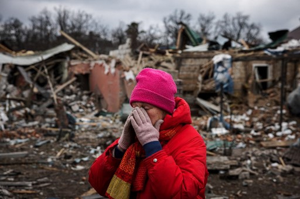 Seorang warga Ukraina menangis di depan sebuah rumah yang hancur terkena serangan Rusia di Irpin dekat Kiev, 13 Maret 2022. (Dimitar DILKOFF / AFP)