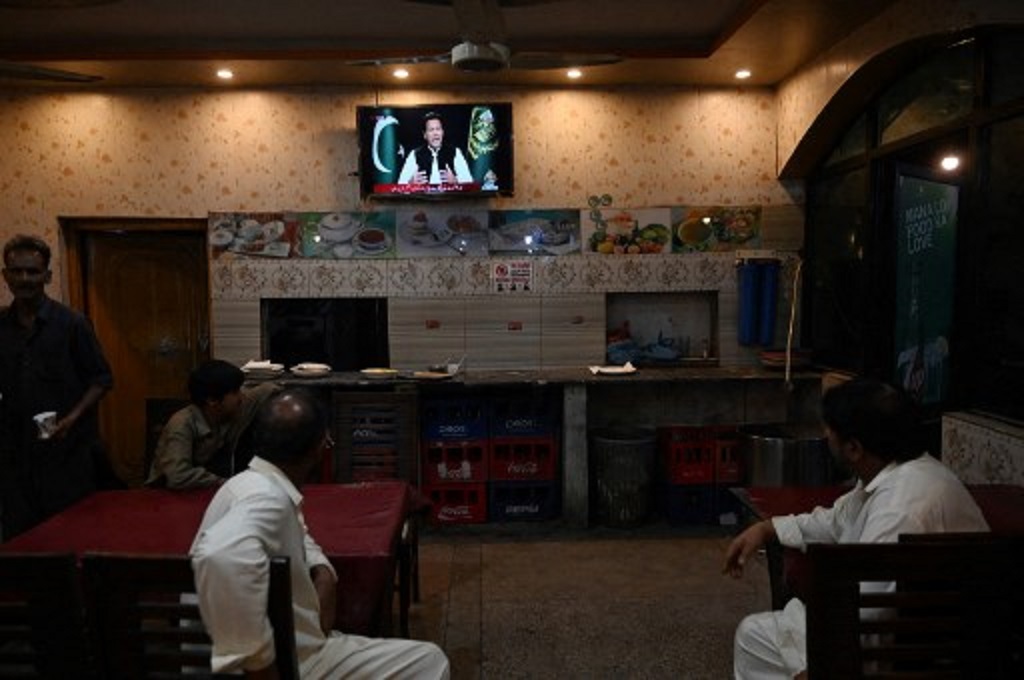 Warga mendengar pidato PM PAkistan Imran Khan di televisi, 8 April 2022. (Aamir QURESHI / AFP)