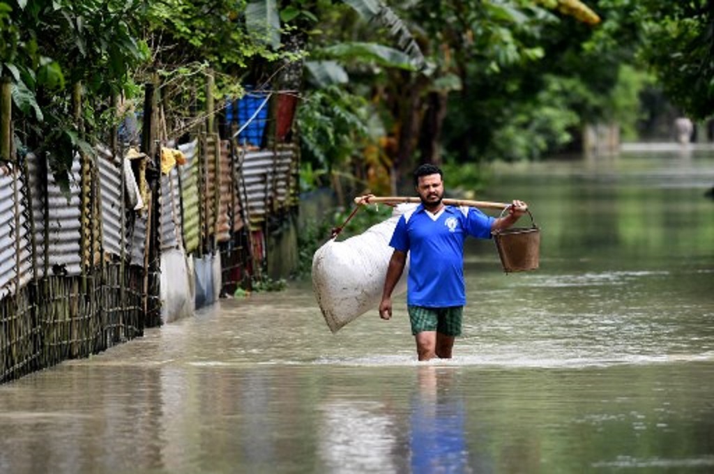 Seorang pria berjalan di tengah banjir di Assam, India, 19 Juni 2022. (Biju BORO / AFP)