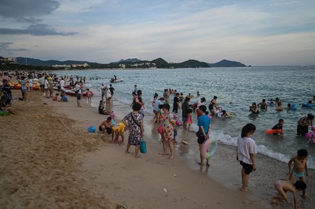 Turis beraktivitas di Sanya, Tiongkok, 18 Juli 2021. (Hector RETAMAL / AFP)