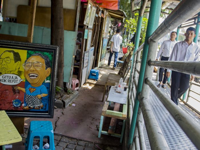 Warga melintas di samping lapak pelukis di Jalan Gedung Kesenian, Pasar Baru, Jakarta.  Foto: ANT/Galih Pradipta