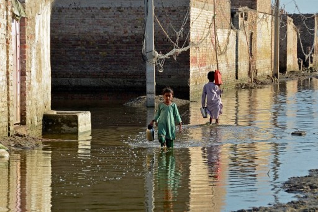 Anak-anak membawa tempat air di tengah banjir di Balochistan, Pakistan, 4 Oktober 2022. (Fida HUSSAIN / AFP)