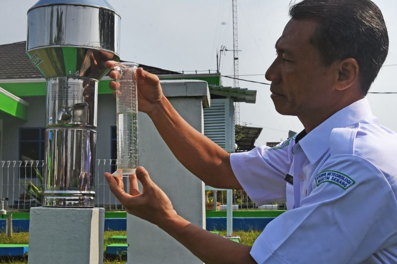 Koordinator Bidang Data dan Informasi Badan Meteorologi, Klimatologi, dan Geologi (BMKG) Stasiun Meteorologi Maritim Kelas I Serang, Tarjono, mengukur volume air hujan di dalam alat pengukur curah hujan. Antara / Asep Fathulrahman