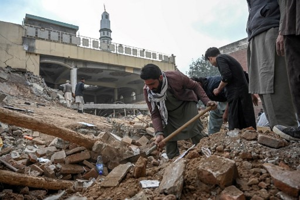 Polisi berpakaian sipil membersihkan puing masjid yang hancur akibat ledakan bom bunuh diri di Peshawar, Pakistan, 1 Februari 2023. (Abdul MAJEED / AFP)